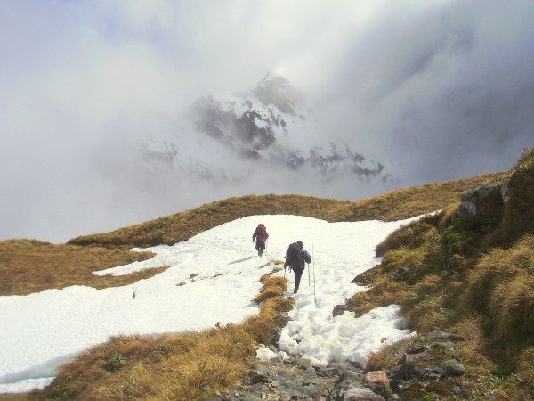 two hikers walking on snow over a mountain pass